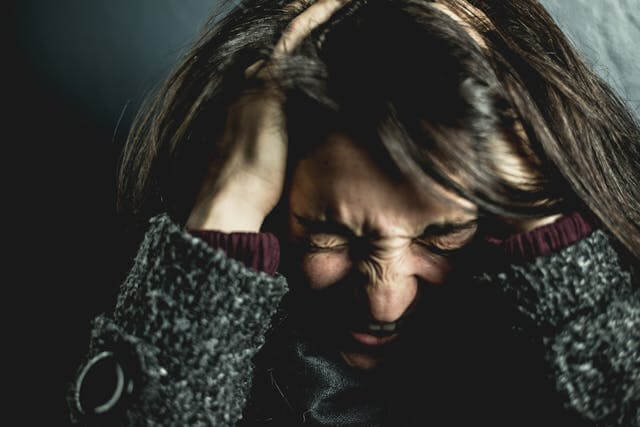 Image of a stressed woman holding her hands in her hair